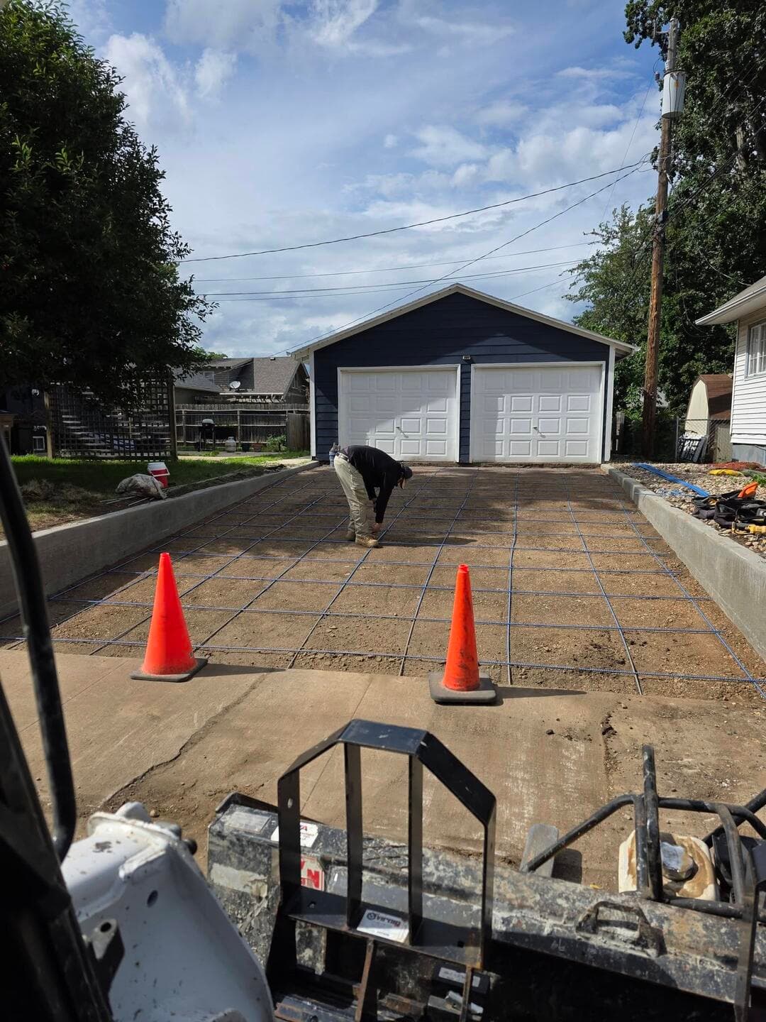 Blue rebar gridded across the graded driveway strip between the formed edges