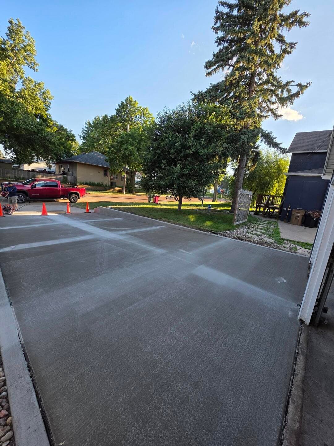 A new broom-finished driveway apron meeting the street, cones guarding the fresh edge