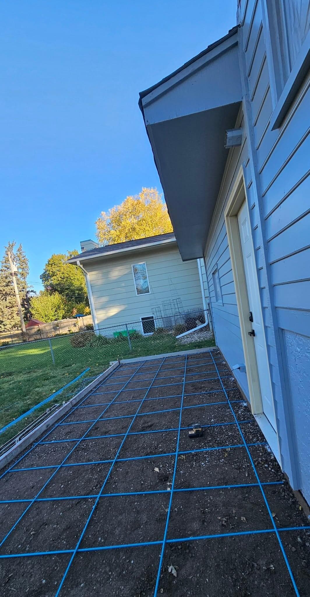 Blue rebar gridded over a compacted side-yard base before the pour