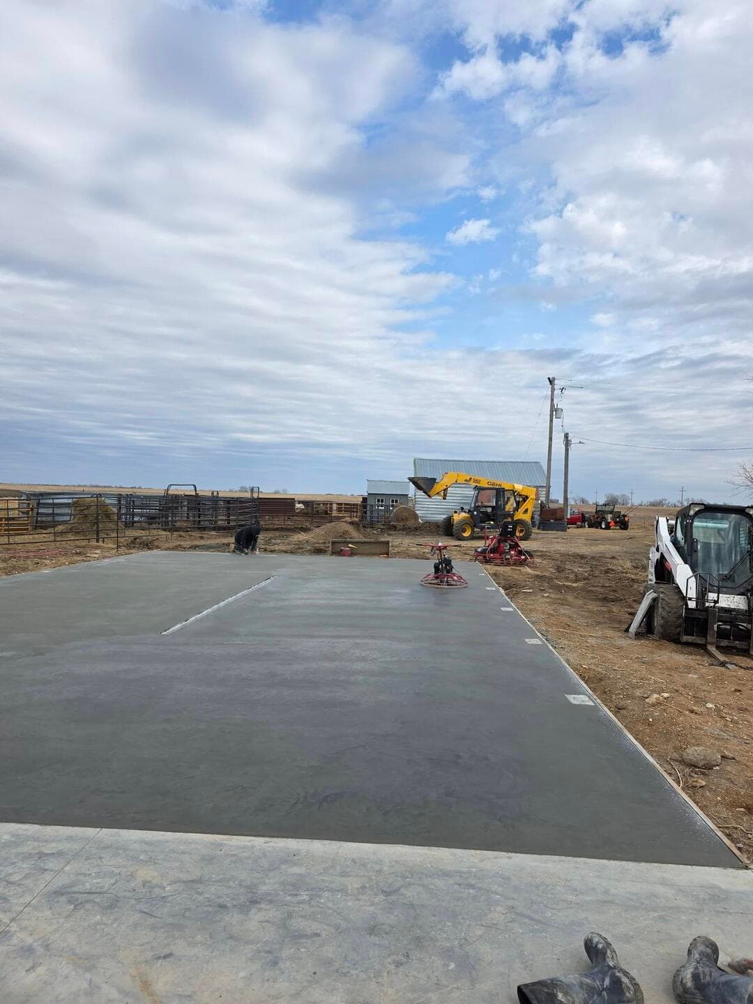 A fresh commercial pad placed and floated, pump and skid steers staged behind