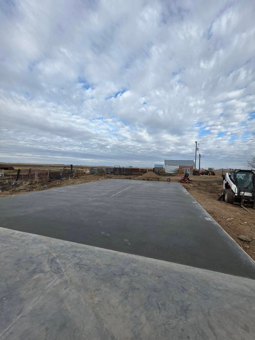 A big finished pad, machine-troweled pale and flat under a farm sky