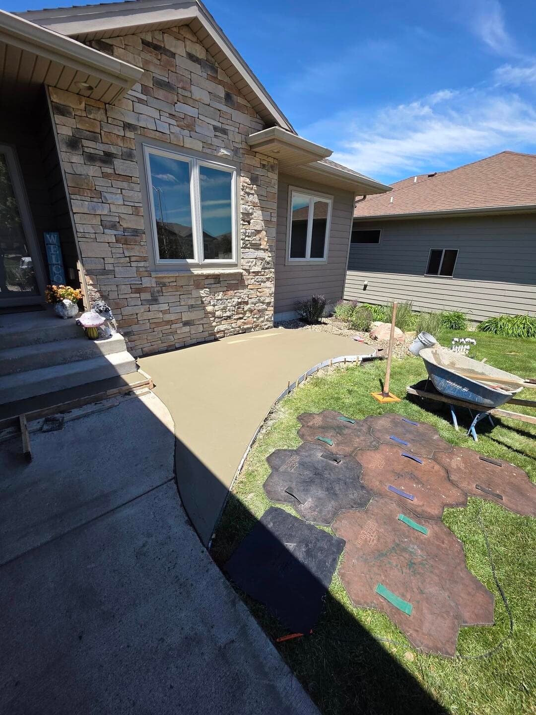 A fresh colored walk poured along the house, flagstone stamp mats laid out on the lawn in the foreground